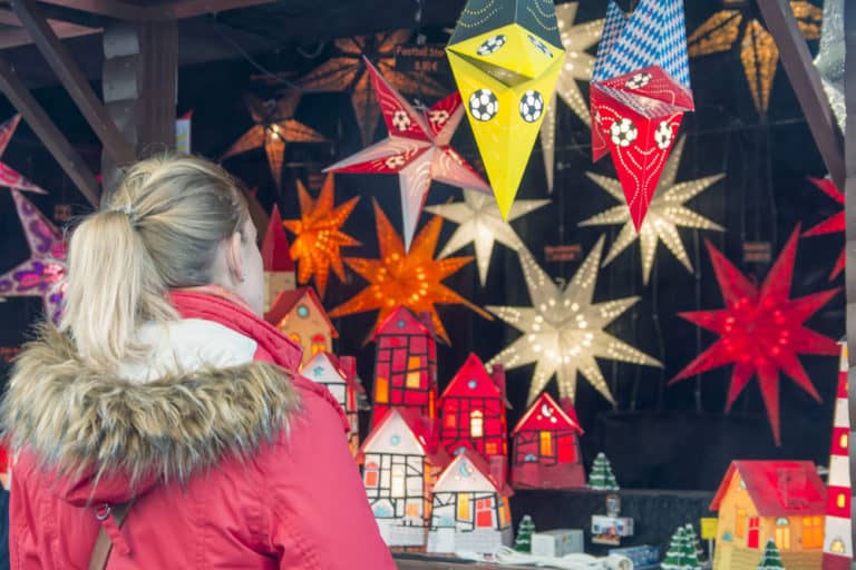 Junges Mädchen bewundert Deko Sterne auf dem Weihnachtsmarkt