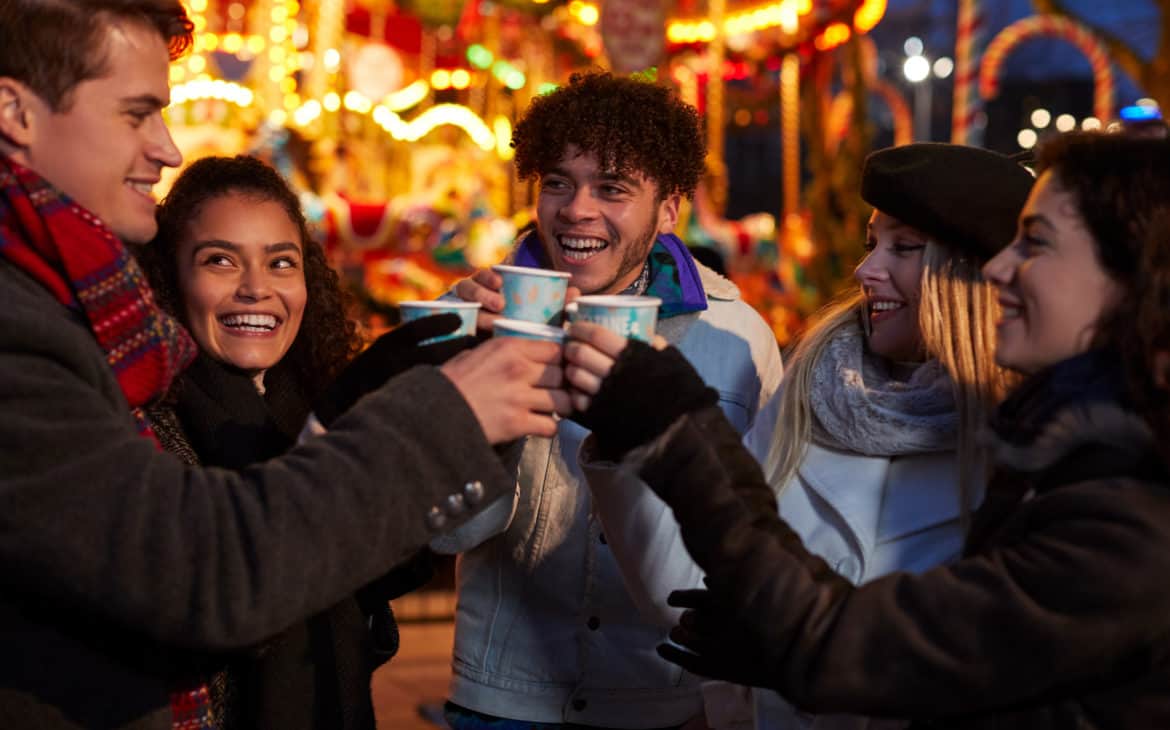 Gruppe junger Meschen beim Glühweintrinken auf dem Weihnachtsmarkt