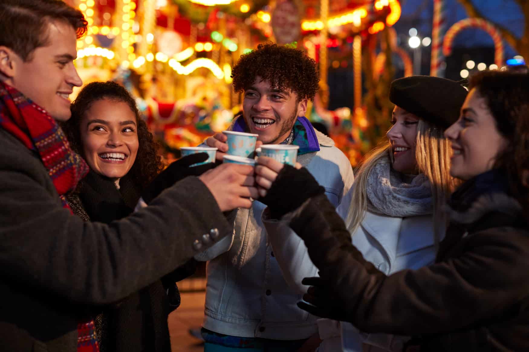 Gruppe junger Meschen beim Glühweintrinken auf dem Weihnachtsmarkt