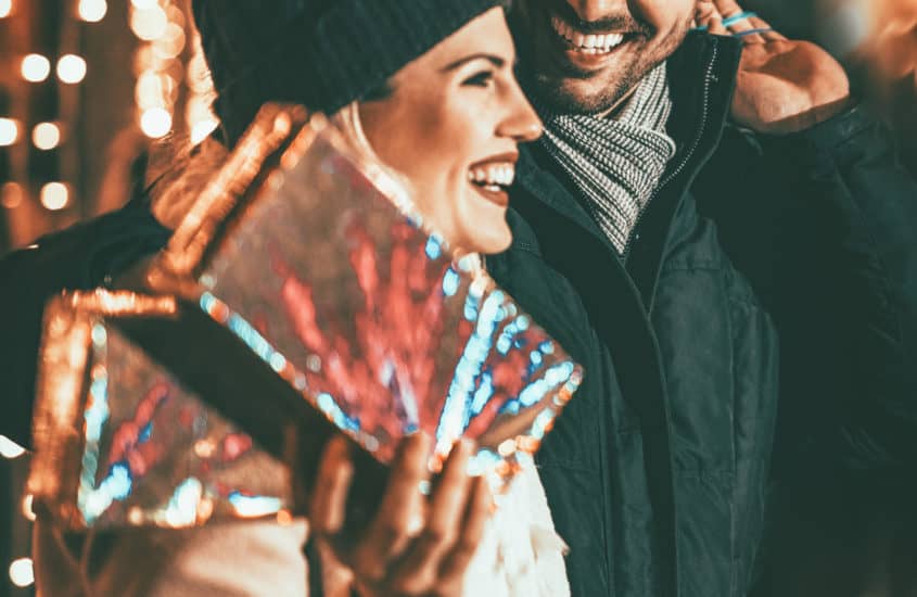 Junge Frau mit Geschenk auf dem Weihnachtsmarkt