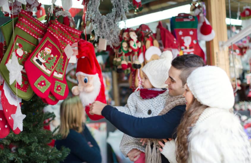 Familie schaut sich Nikolausfiguran auf dem Weihnachtsmarkt an