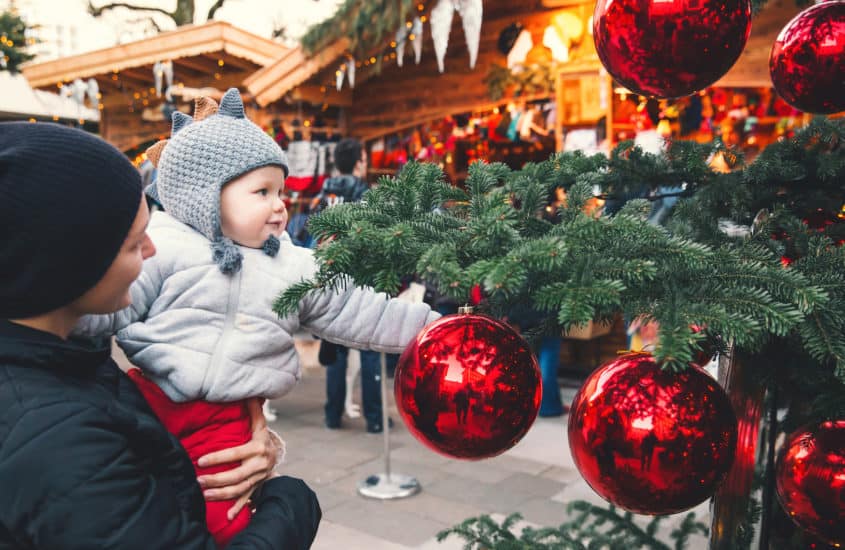 Kind schaut staunend auf die Christbaumkugel