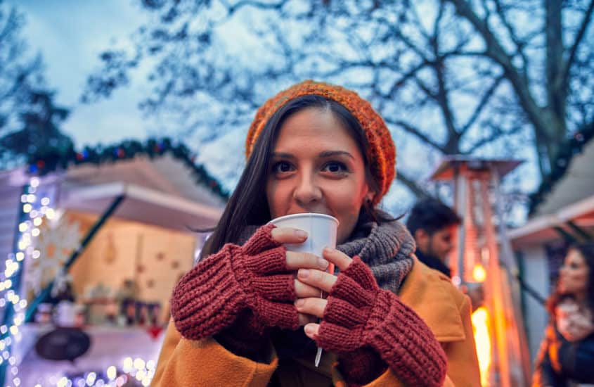 Dame trinkt Glühwein auf dem Weihnachtsmarkt