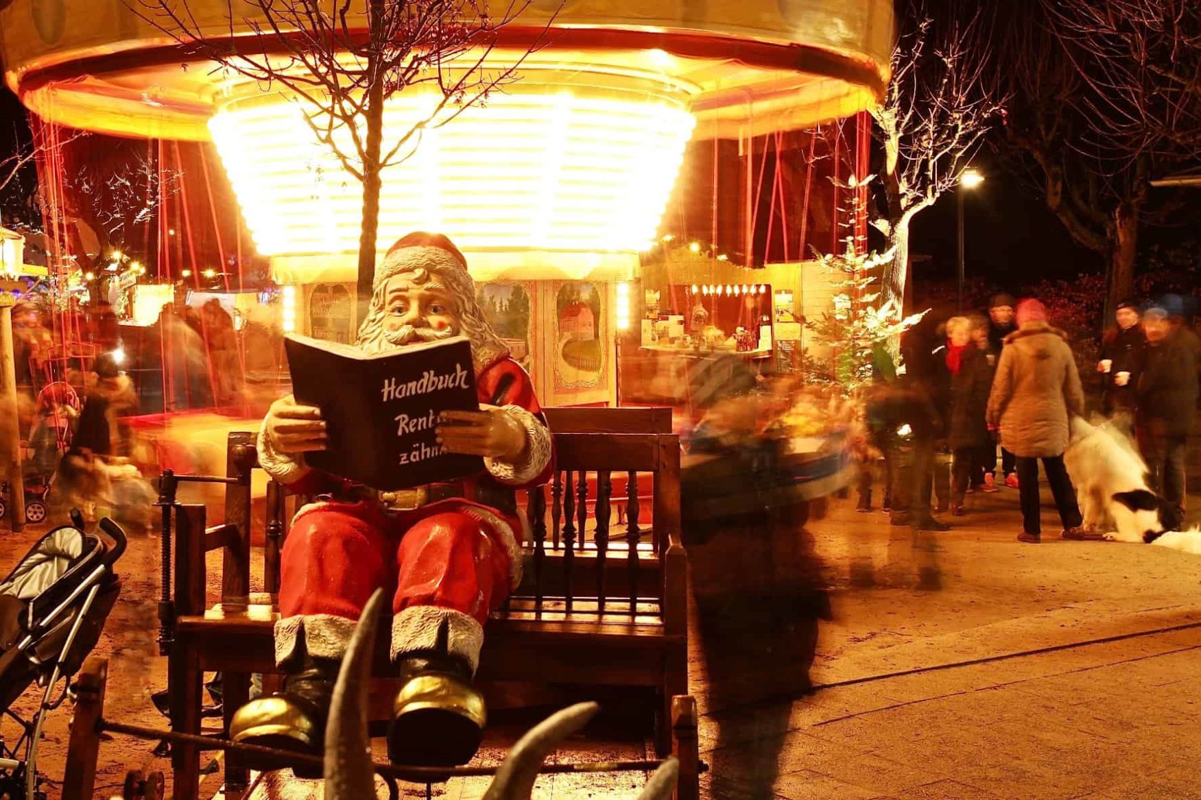 Nikolaus sitzt auf der Bank am Weihnachtsmarkt