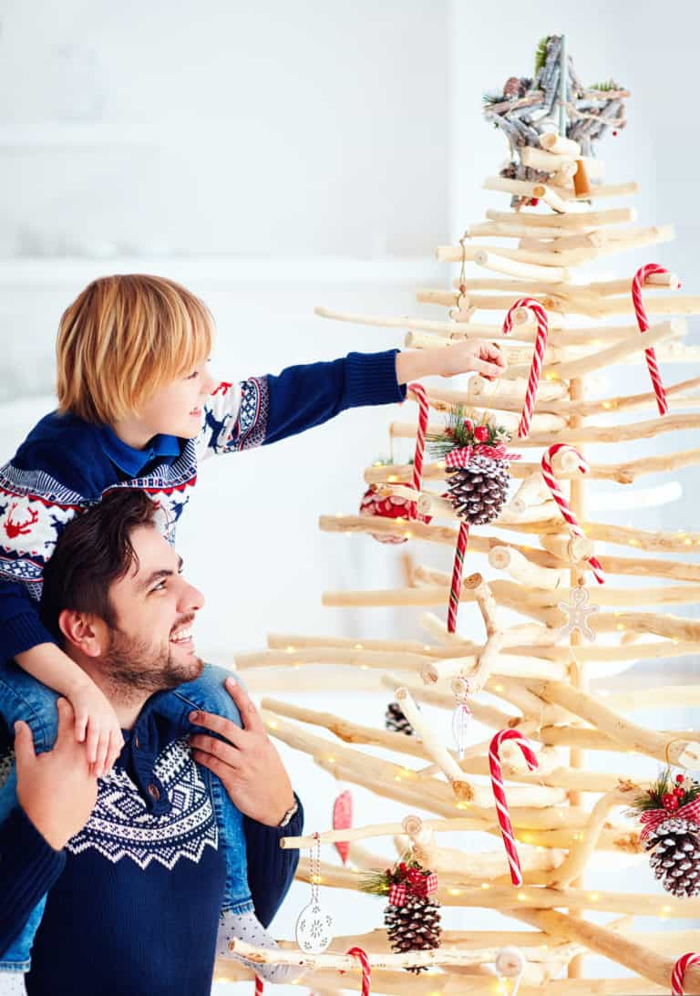 Vater und Sohn schmücken alternativen Weihnachtsbaum aus Holz