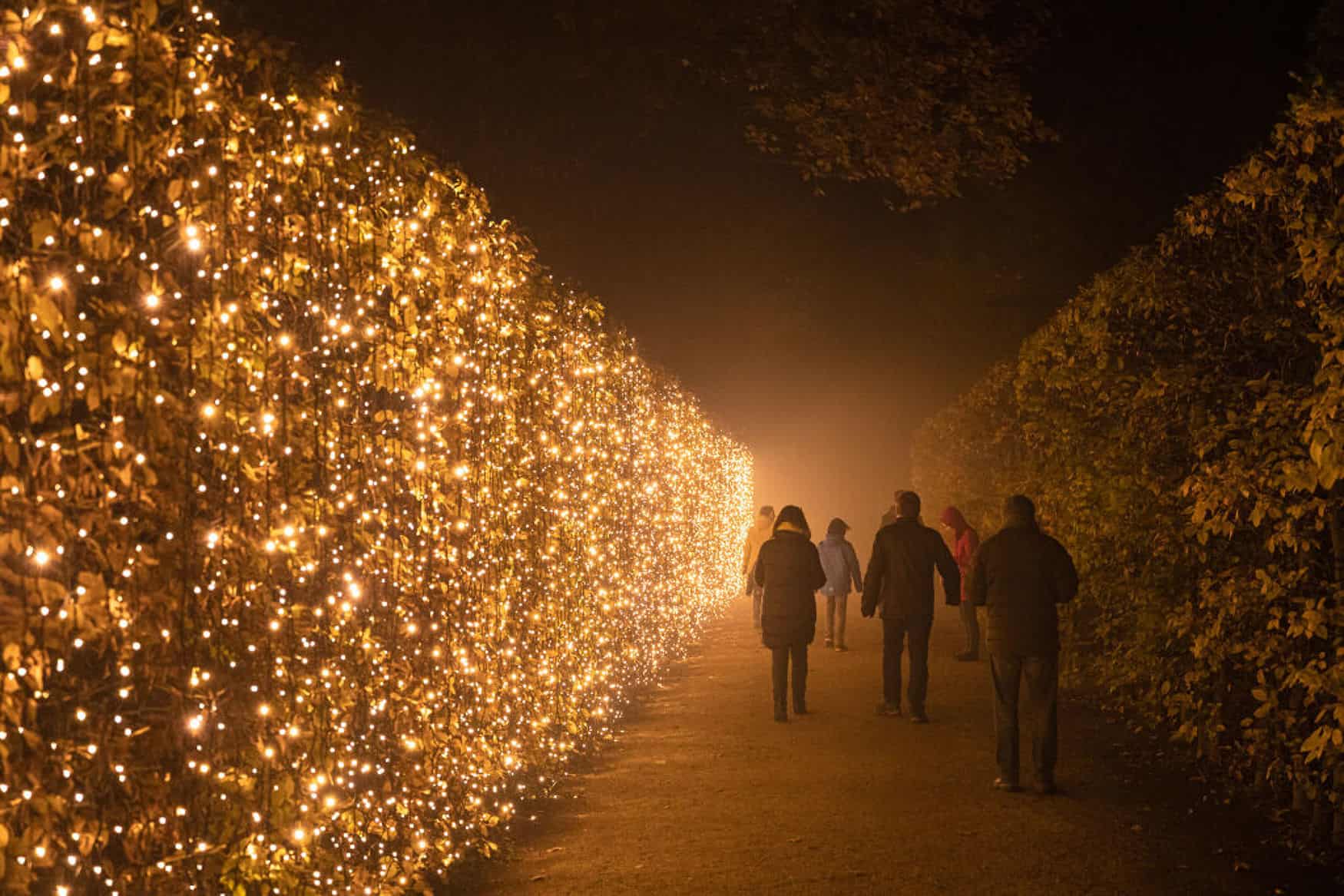 Menschen spazieren im Dunkeln zwischen den mit Lichtern geschmückten Hecken der Festung Ehrenbreitstein bei Koblenz.