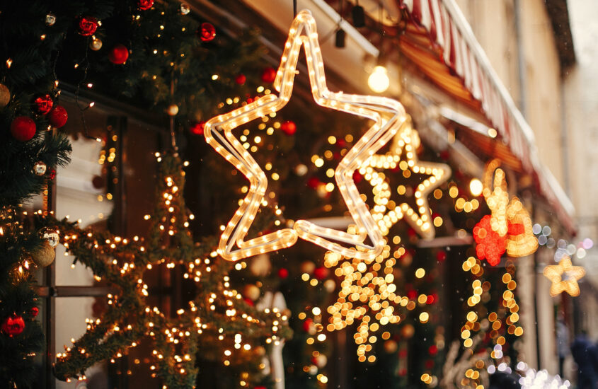 Sterne aus Lichterketten und mit Lichtern geschmücktes Tannengrün verzieren ein Haus festlich zur Weihnachtzeit.