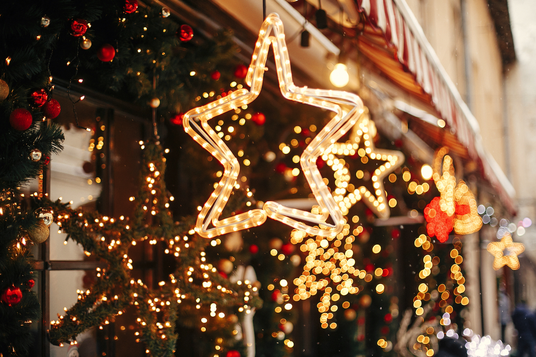 Sterne aus Lichterketten und mit Lichtern geschmücktes Tannengrün verzieren ein Haus festlich zur Weihnachtzeit.