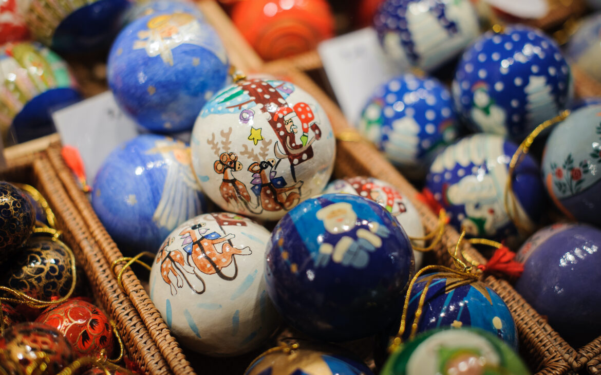Blaue und weiße Christbaumkugeln liegen in einem Korb in einem Stand auf dem Weihnachtsmarkt.