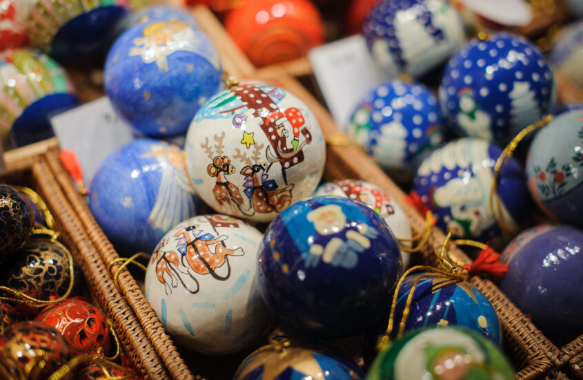 Blaue und weiße Christbaumkugeln liegen in einem Korb in einem Stand auf dem Weihnachtsmarkt.