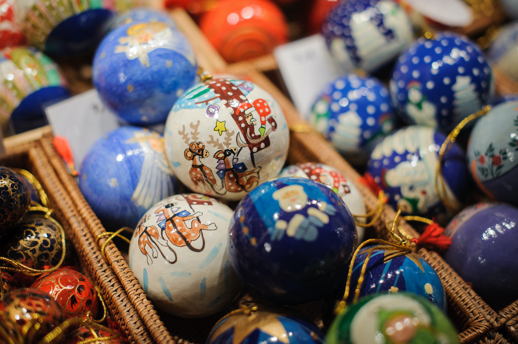 Blaue und weiße Christbaumkugeln liegen in einem Korb in einem Stand auf dem Weihnachtsmarkt.