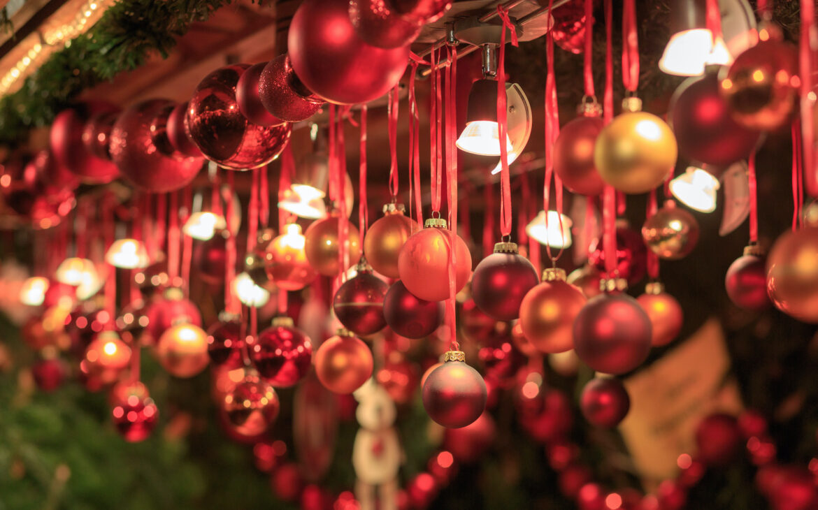 Von einem Stand auf dem Weihnachtsmarkt hängen verschiedene Christbaumkugeln in unterschiedlichen Rottönen.