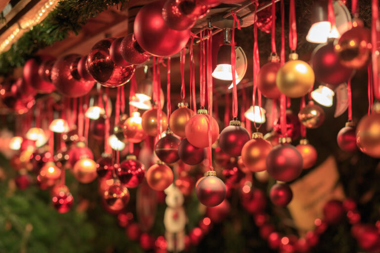 Von einem Stand auf dem Weihnachtsmarkt hängen verschiedene Christbaumkugeln in unterschiedlichen Rottönen.