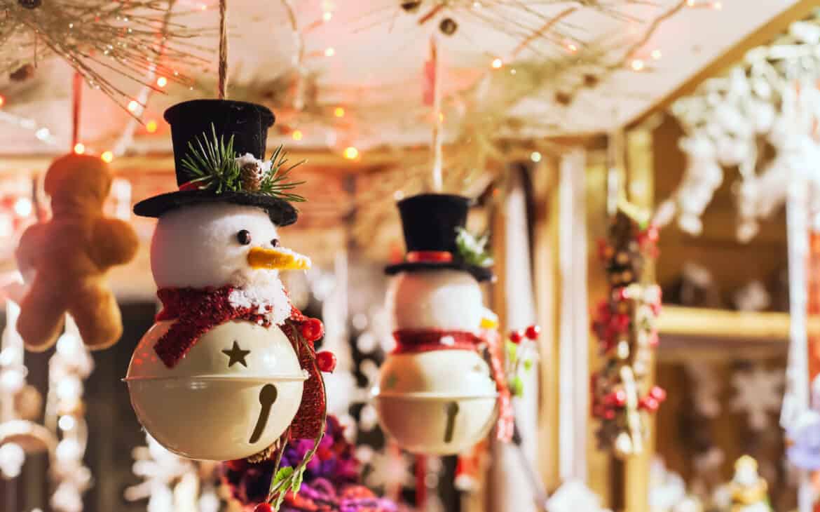 In einem Stand auf dem Weihnachtsmarkt hängen Schneemänner-Glöckchen als Dekorationsaufhänger für die Weihnachtszeit.