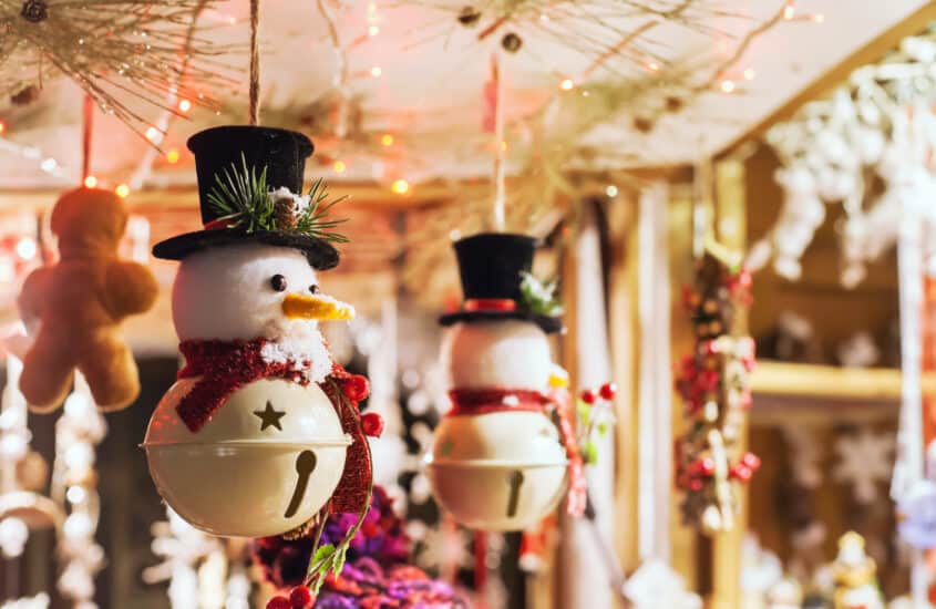 In einem Stand auf dem Weihnachtsmarkt hängen Schneemänner-Glöckchen als Dekorationsaufhänger für die Weihnachtszeit.