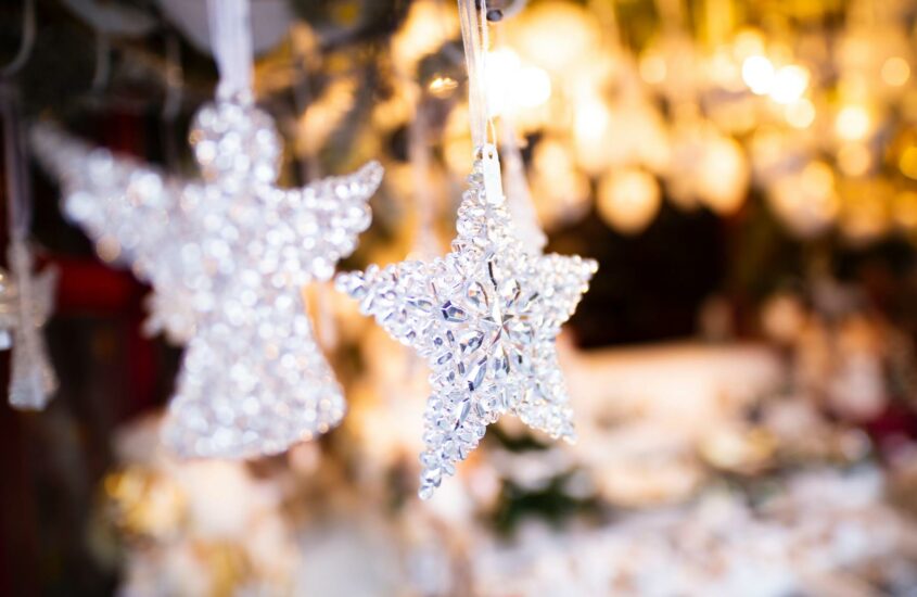Ein Engel und ein Stern aus Kristallen hängen als festlicher Christbaumschmuck in einem Stand auf dem Weihnachtsmarkt.