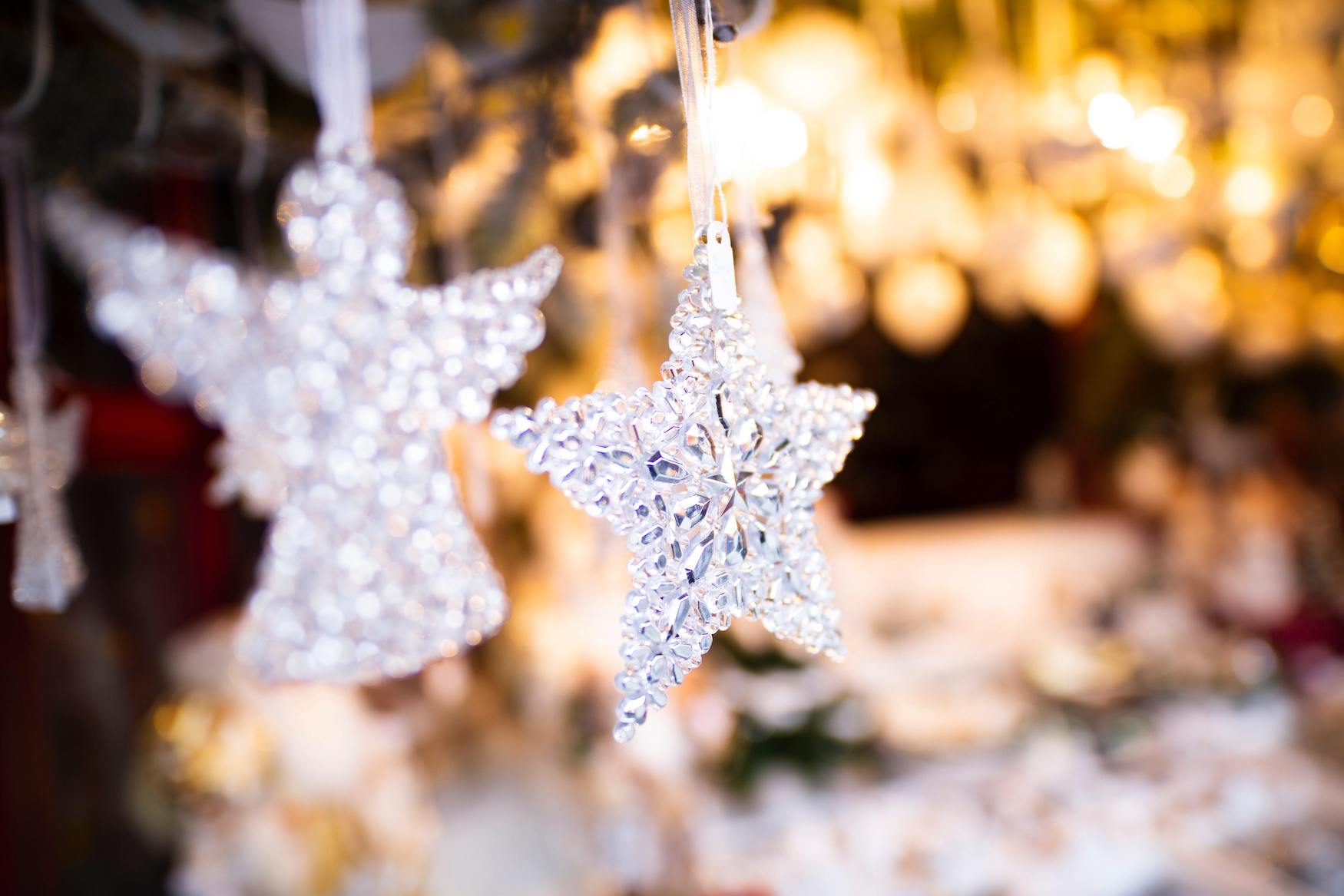 Ein Engel und ein Stern aus Kristallen hängen als festlicher Christbaumschmuck in einem Stand auf dem Weihnachtsmarkt.