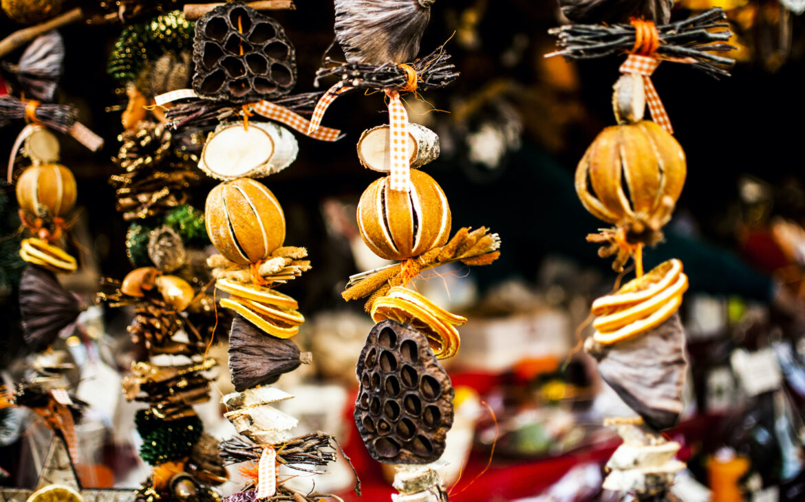 Weihnachtsschmuck aus Orangen und anderen Elementen aus der Natur hängen an einem Stand auf dem Weihnachtsmarkt.