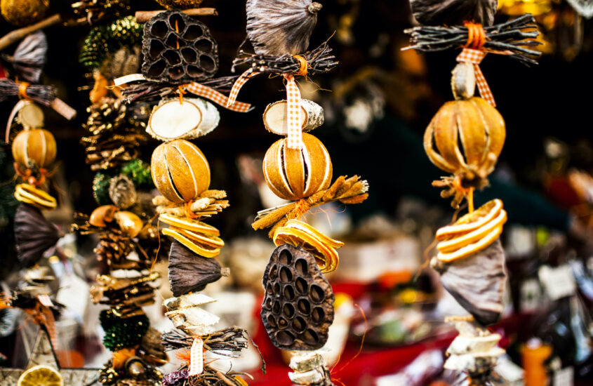 Weihnachtsschmuck aus Orangen und anderen Elementen aus der Natur hängen an einem Stand auf dem Weihnachtsmarkt.