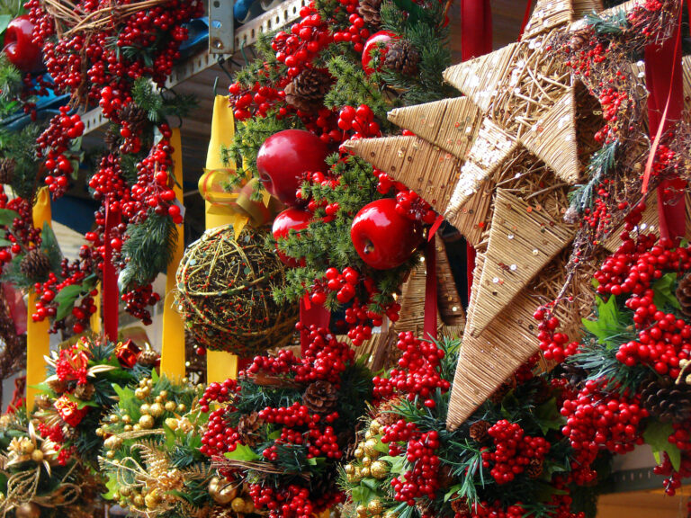 Ein Stand auf dem Weihnachtsmarkt ist festlich mit Sternen, Moos, roten Beeren und Äpfeln geschmückt.
