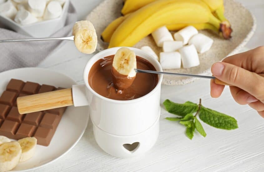 Banane wird in Schokoladenfondue gehalten