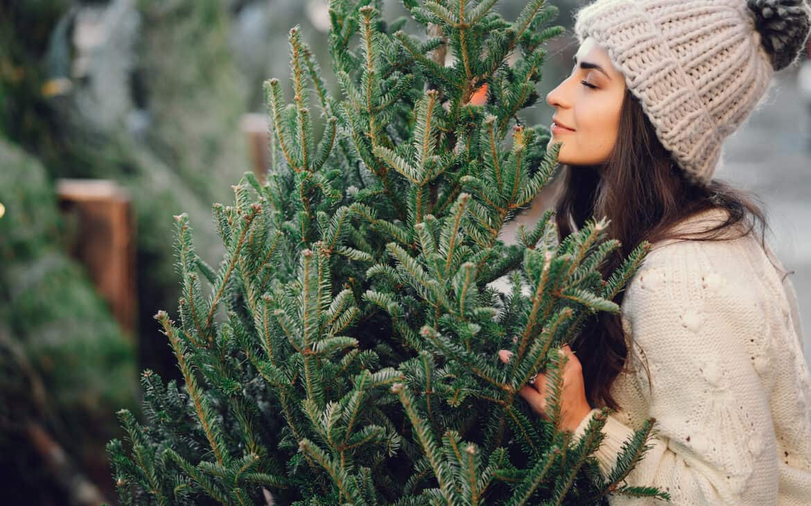 Frau in weißem Strickpulli beim Weihnachtsbaumkauf