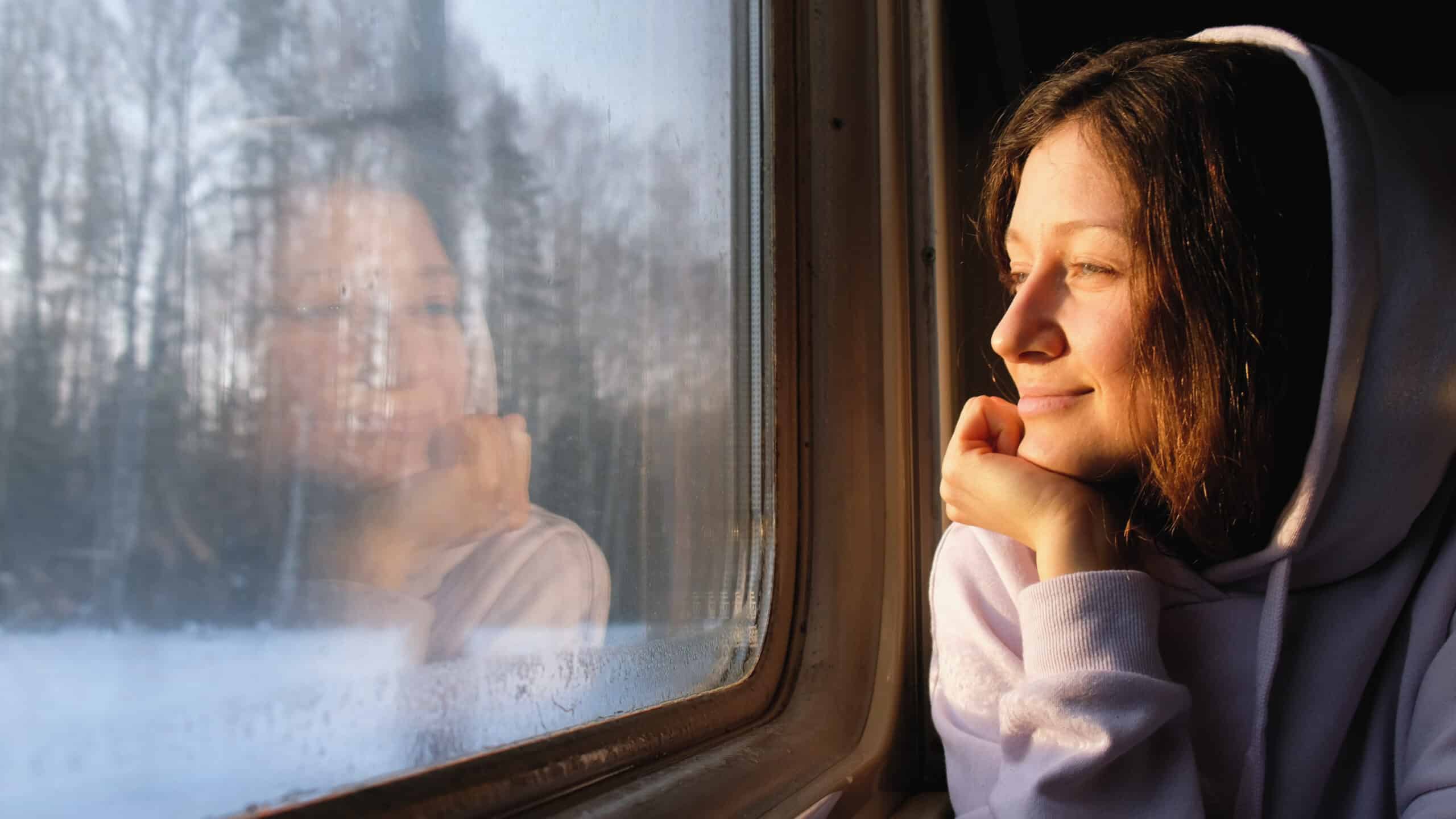 Mädchen im Zug guckt aus dem Fenster in eine winterliche Landschaft