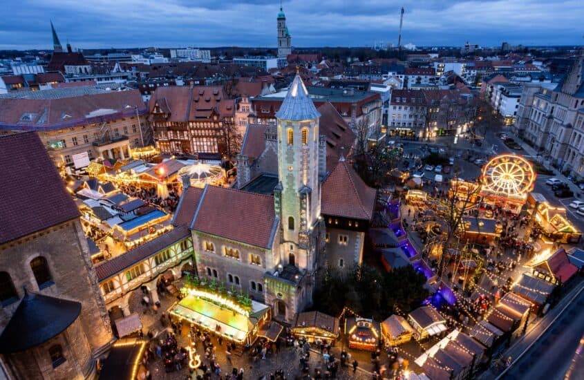 Weihnachtsmarkt Braunschweig von oben in der Abenddämmerung mit beleuchteter Burg Dankwarderode, Dom St. Blasii, Riesenrad, Karussell und Buden