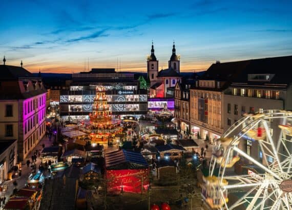 Weihnachtsmarkt Fulda von oben in der Abenddämmerung mit Weihnachtspyramide, Buden, Riesenrad und barocker Kirche