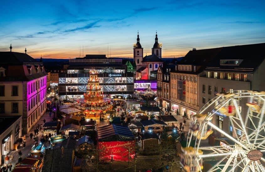 Weihnachtsmarkt Fulda von oben in der Abenddämmerung mit Weihnachtspyramide, Buden, Riesenrad und barocker Kirche